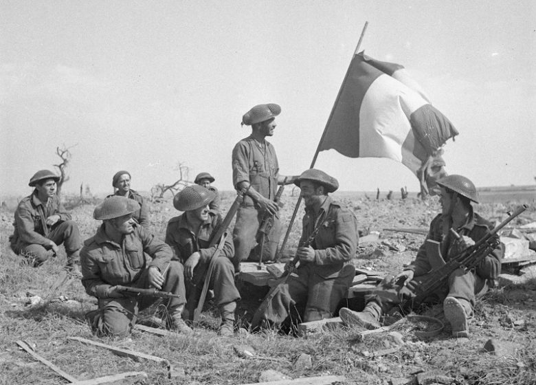 Le caporal Robert Morin, des Fusiliers Mont-Royal, lève un drapeau français au-d